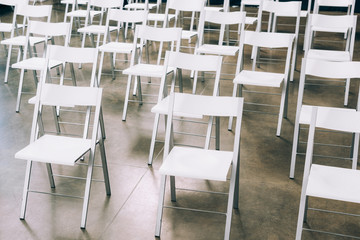 close up view of arranged empty white chairs in conference hall