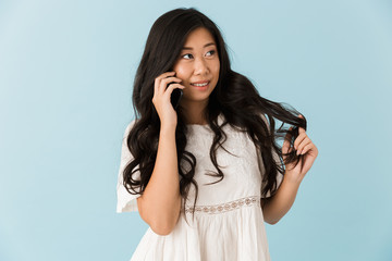 Fototapeta premium Asian beautiful woman isolated over blue background talking by mobile phone.