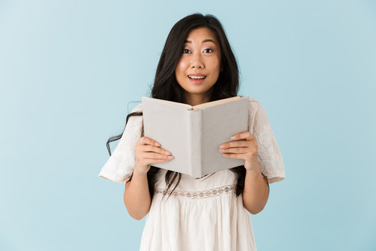 Asian beautiful woman isolated over blue background reading book.