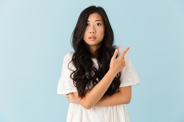 Fototapeta premium Scared young asian beautiful woman posing isolated over blue background pointing.