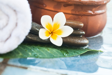 Tropical white Flower and stones for massage treatment on blue background.