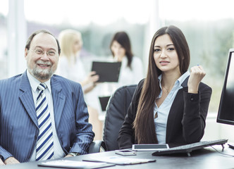boss and members of the business team sitting at workplace on background of office