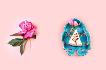 cheesecake on a a decorative blue plate with flower cuddly pions, pink background. Flat lay. Copy space