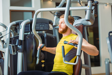 Portrait of a handsome bodybuilder smiling and looking at camera while exercising at a modern...