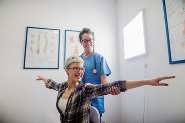 Orthopedist examing patient. Patient holding  open arms and sitting on a chair.