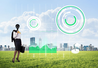 Camera headed woman standing on green grass against modern cityscape