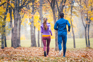 Couple jogging or running in colorful foliage, seen from behind