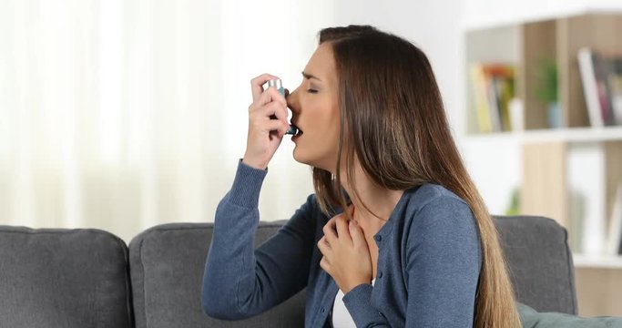 Woman suffering an asthma attack and uses a inhaler at home