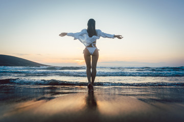 Woman enjoying the freedom of her vacation at the sea in a sunset mood