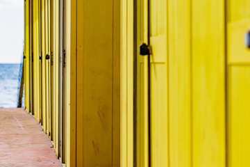 Beautiful yellow Bathing houses on sandy beach. Empty shelters on a sunny but moody day. Seaside architecture, colored paint, maze like labyrinth. Homelessness and lonely places.