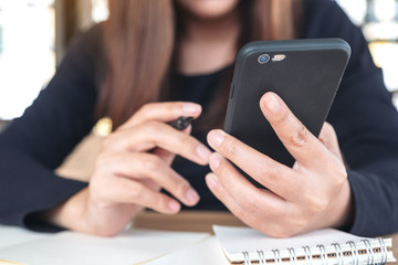 Closeup image of a woman holding , using and looking at smart phone while working