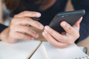 Closeup image of a woman holding , using and looking at smart phone while working