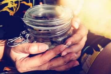 Money in glass jar on hand