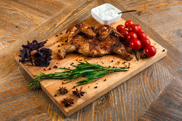 Grilled chicken on a wooden tray with cherry tomatoes and garlic sauce