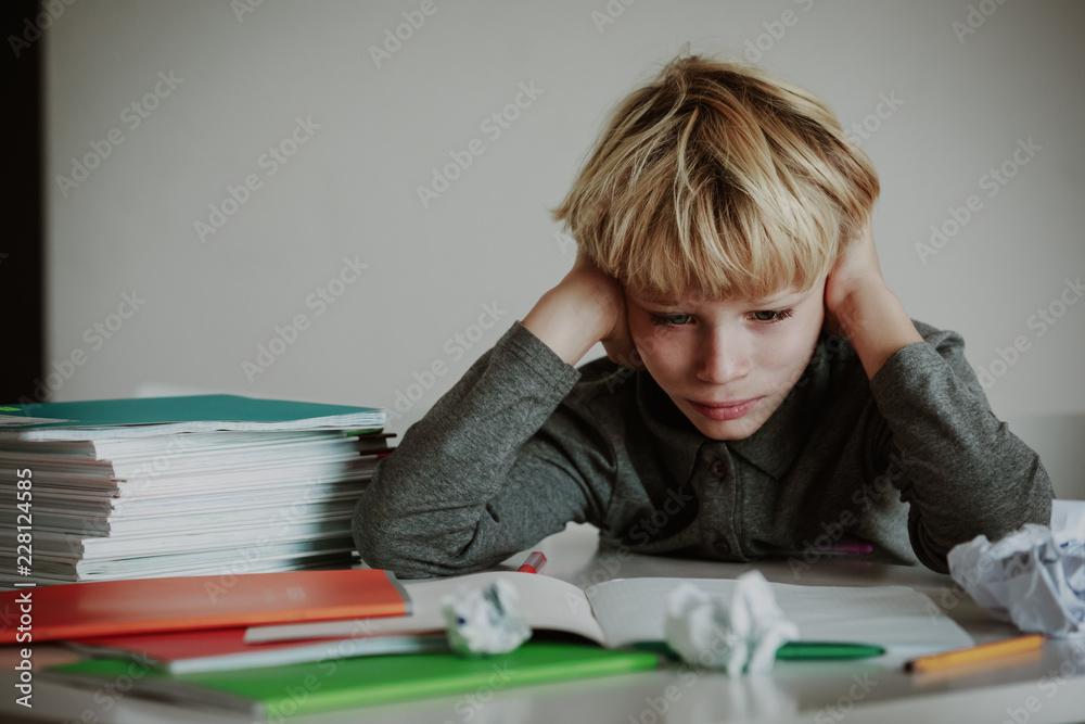 Wall mural little boy tired stressed of doing homework, bored, exhausted