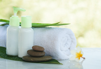 Obraz na płótnie Canvas Spa or wellness setting with tropical flower with sunlight, towel and cream tube. Body care and spa concept outdoors