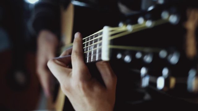 Closeup footage on hands playing an acoustical guitar