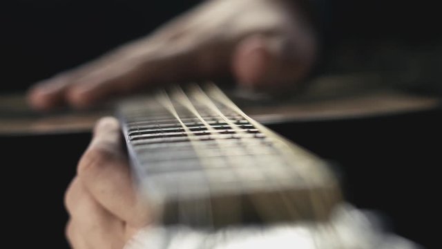 Man hand stroking guitar strings