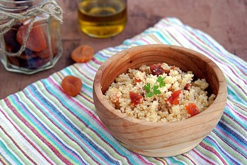 Couscous with dried apricots and fried onions in a wooden bowl. Traditional Moroccan dish. Healthy food.