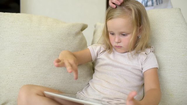 Child watching ang using tablet at home. Children using a modern laplop, tablet on sofa. Little girl playing on the tablet computer games, watching videos, cartoons. slow-motion
