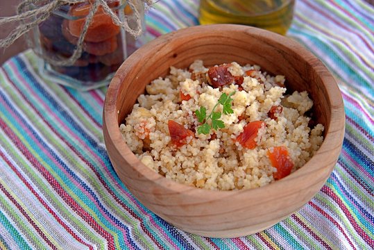 Couscous with dried apricots and fried onions in a wooden bowl. Traditional Moroccan dish. Healthy food.