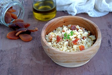 Couscous with dried apricots and fried onions in a wooden bowl. Traditional Moroccan dish. Healthy food.