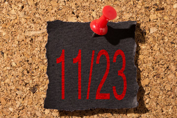 Bulletin board. Thumbtack in black paper. Reminder about Black Friday. Text: 11/23