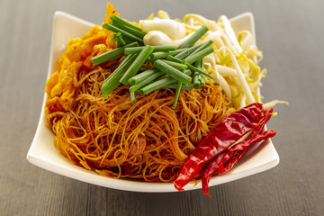 Fried noodles with bean sprouts and spring onion on wood texture