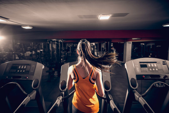 Sporty woman running on treadmill. Gym interior.