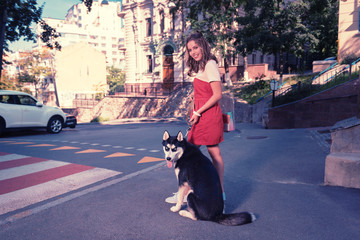 Woman and husky. Young beautiful beaming woman wearing fashionable red summer dress taking her cute dark husky for a walk