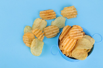 Different types of chips in a blue bowl on a bright blue background. view from above