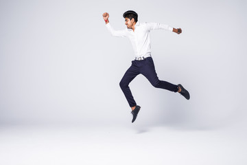Full length of young indian man cheering and jumping isolated over white background