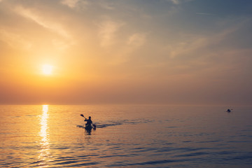Naklejka premium Beautiful Black sea sunrise in Odessa with silhouette of kayaking man and warm colors
