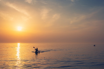 Beautiful Black sea sunrise in Odessa with silhouette of kayaking man and warm colors