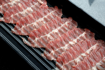 Raw Beef sliced for Shabu or Sukiyaki in black plate on the table background. Foods concept.