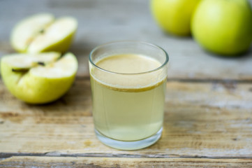 Homemade fresh squeezed apple juice in a clear glass with apple on a side