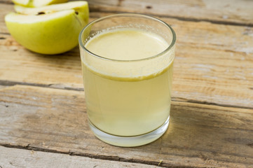 Homemade fresh squeezed apple juice in a clear glass with apple on a side