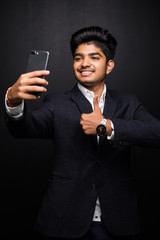Smiling young man taking selfie photo on smartphone. Indian guy using digital device. Selfie photo concept.