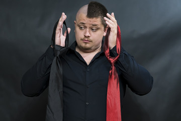 Punk. On the hands hang two ties. Facial expression is indecisive and thoughtful. The look is...
