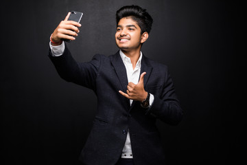 Obraz na płótnie Canvas Cheerful excited Indian guy gesturing while posing for selfie. Positive young bearded blogger talking to followers using modern gadget. Selfie concept