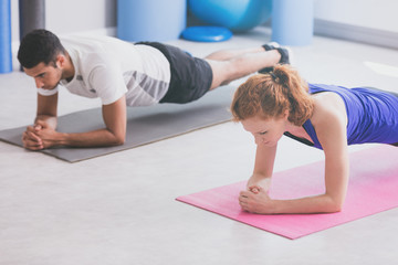 Girl and boy doing plank on a gym