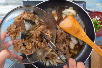 Chef put slice of cooked beef to pan