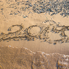 2019 - the date of the new year is written on the yellow sand by the sea or ocean. The concept of the New Year holidays and the onset of the new year twenty nineteen. Background