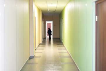 Fototapeta na wymiar Corridor in school silhouette of a man. A school age child is walking down the hall.