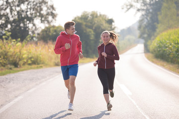 young couple jogging along a country road