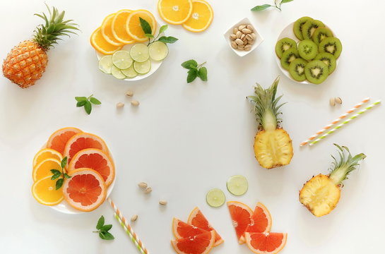 Summer tropical fruits composition table  top view background. . Pineapples, kiwi, lime, grapefruit, orange,  pistachios on white background. Summer food concept. Flat lay,  copy space
