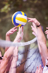 group of young friends playing Beach volleyball