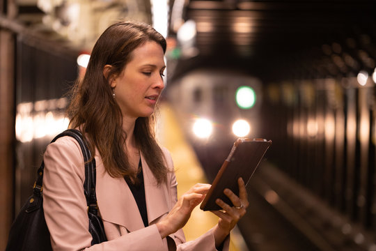 Business Woman In City Using Tablet Computer On Subway Platform