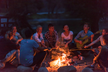 young friends relaxing around campfire