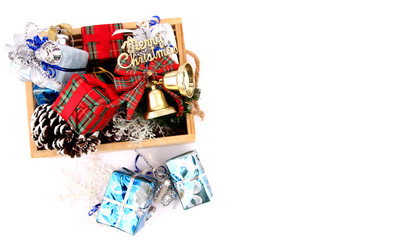 Gifts and decorations in a basket on Christmas Eve with white backdrop.